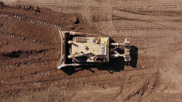 Bulldozer pushing large amount of fresh soil, Aerial follow footage.
