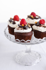 Chocolate muffins with fresh raspberries on the table, light background with space text. Selective focus.