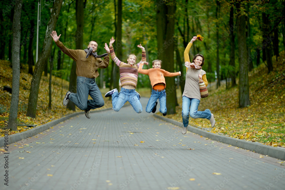 Wall mural Family of four jumping in autumn park