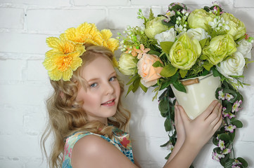 girl blonde in a wreath of yellow flowers and with flowers in the root in her hands