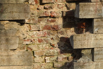 The background of the destroyed brickwork is visible in the fracture of the decorative wall cladding. Natural and artificial destruction of historic buildings.