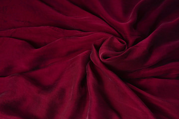 Soft smooth burgundy silk fabric background. Fabric texture.