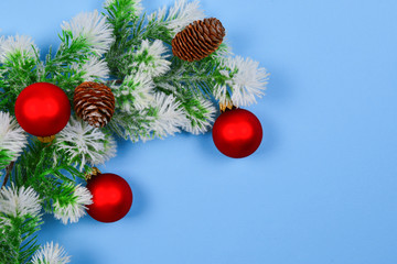 A sprig of spruce decorated with red Christmas ball on a blue background. Copy space.