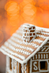 Gingerbread house on table. Defocused lights of Christmas garland. Morning in the bright living room. Holiday mood