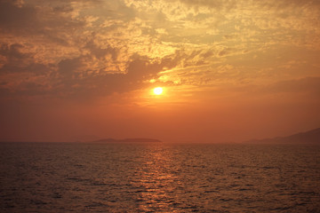 Fototapeta premium Beautiful sunset over Aegean sea with some clouds and golden colours