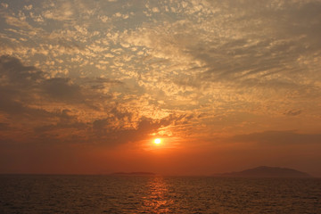 Beautiful sunset over Aegean sea with some clouds and golden colours