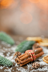 Cinnamon and christmas decoration on wooden table. Spruce branch, orange and snow. Morning in the bright living room. Holiday mood.