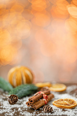 Cinnamon and christmas decoration on wooden table. Spruce branch, orange and snow. Morning in the bright living room. Holiday mood.