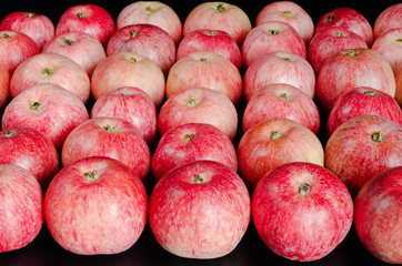 Background image with ripe red apples lying on a black background