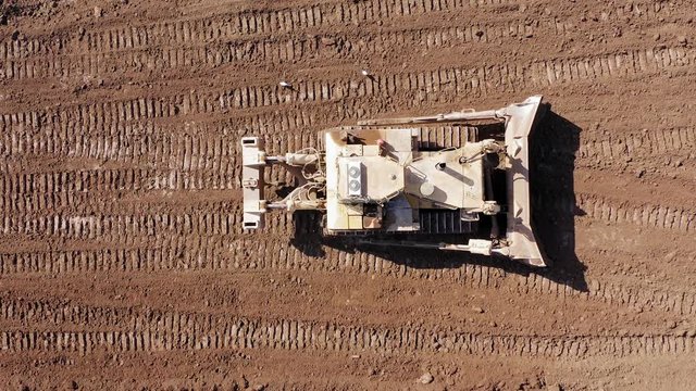 Bulldozer pushing large amount of fresh soil, Aerial follow footage.