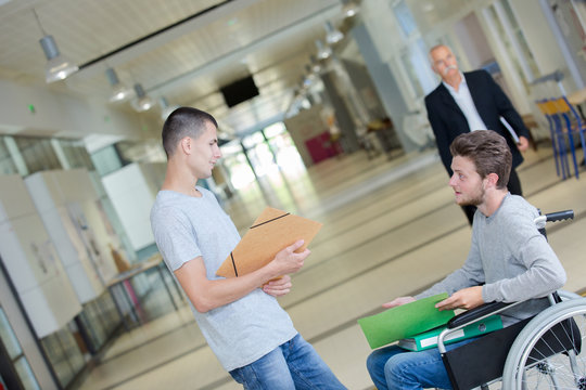 thoughtful disabled schoolboy on wheelchair in corridor at school