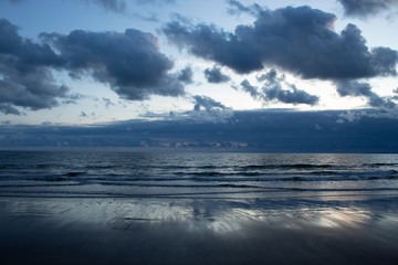 Low tide sea with clouds and reflection on sand