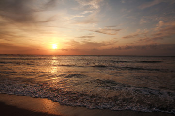 Fototapeta na wymiar Colorful sunset over the sea coast on sky and clouds background