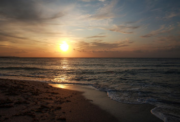 Colorful sunset over the sea coast on sky and clouds background