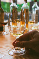 Glass of white porto wine and man's hand bottles behind