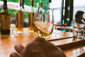 Glass of white porto wine in motion with bottles of wine 