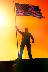 Silhouette of man holding US flag American on the mountain. The concept of Independence Day. a successful silhouette winner, a man waving an American flag on top of a mountain peak