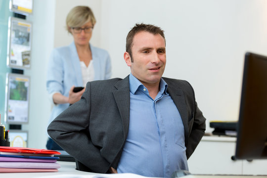 man at office desk stretching out his back