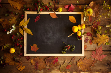 Autumn composition with blackboard,dry leaves gifts and berries