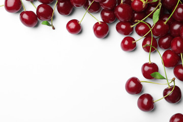 Naklejka na ściany i meble Tasty ripe cherries with leaves on white background, top view