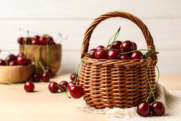 Fototapeta na wymiar Wicker basket of delicious cherries on wooden table against white background, space for text