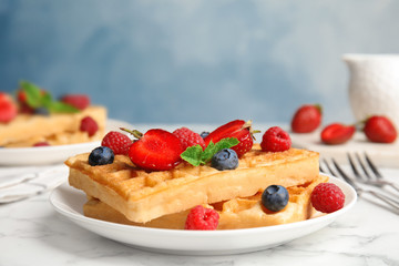 Delicious waffles with fresh berries served on white marble table