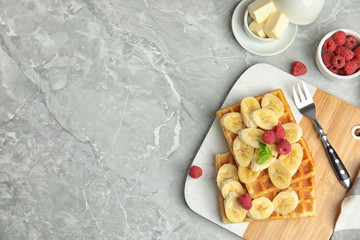 Flat lay composition with delicious waffles and fresh berries on white marble table. Space for text