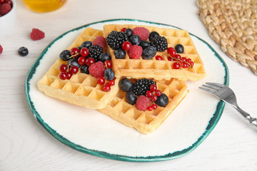 Delicious waffles with fresh berries served on white wooden table
