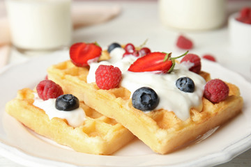 Delicious waffles with fresh berries served on white wooden table, closeup