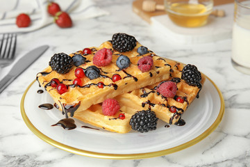 Delicious waffles with fresh berries served on white marble table