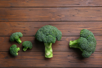 Flat lay composition of fresh green broccoli on wooden table, space for text