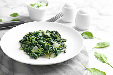Plate with tasty cooked spinach on table. Healthy food