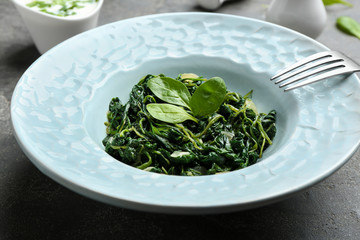 Plate with tasty spinach on grey  table, closeup. Healthy food