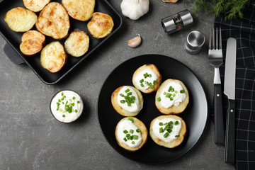 Delicious potato wedges with sour cream dressing on grey table, flat lay