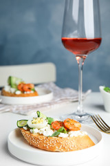 Delicious bruschetta with shrimps served on white table against blue background