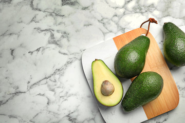 Delicious ripe avocados on marble table, flat lay. Space for text