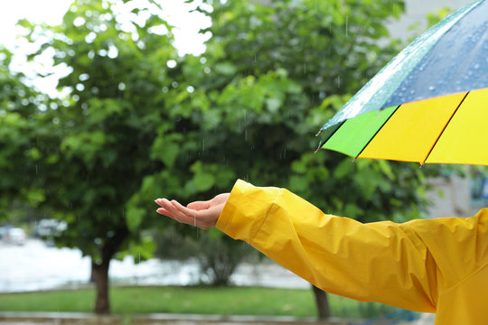Woman with colorful umbrella outdoors on rainy day, closeup