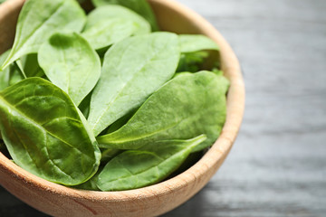 Bowl of fresh green healthy spinach on dark wooden table, closeup