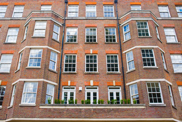 Fototapeta na wymiar Facade of anonymous English British apartments residential building in red bricks