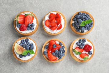 Fototapeta na wymiar Delicious sweet pastries with berries on grey table, flat lay
