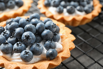 Delicious sweet pastry with berries on cooling rack, closeup