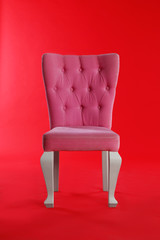 Stylish pink chair on red background. Element of interior design