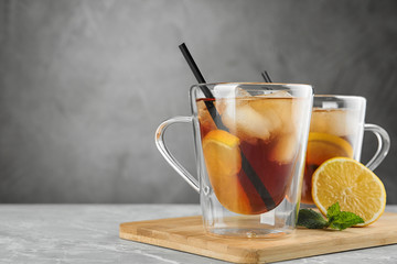 Cups of refreshing iced tea on marble table against grey background. Space for text