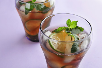 Glasses of refreshing iced tea on lilac background, closeup