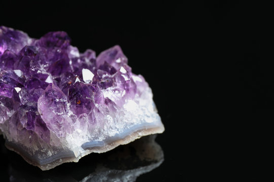 Beautiful purple amethyst gemstone on black background, closeup. Space for text