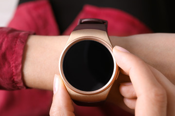 Young woman checking modern smart watch, closeup