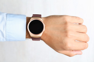 Young man with smart watch on light background, closeup