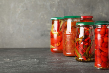 Jars of tasty pickled vegetables on grey table. Space for text
