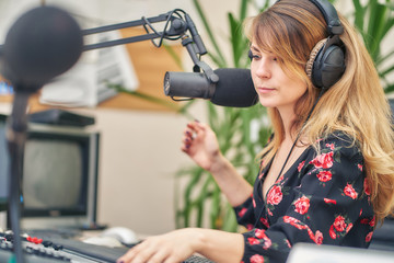 girl radio host with headphones speaks into a microphone on a radio station and reads a script