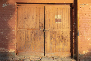 Wooden gate. A gate in an old brick wall with peeling paint.